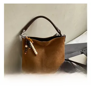 Detail view of large brown faux suede tote bag with decorative wooden beads and leather trim