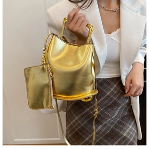 Detailed view of golden metallic bucket bag with geometric handle and matching pouch