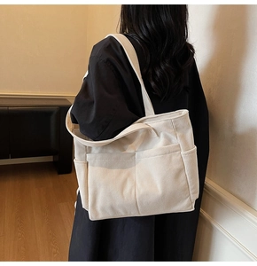 Détail du sac cabas en velours côtelé blanc montrant les poches et la texture nervurée