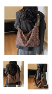 Detail of leopard print hobo tote bag with zipper closure and brown leather shoulder strap