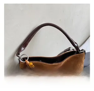 Detail of brown suede tote bag featuring polished leather handle and vintage beaded charm