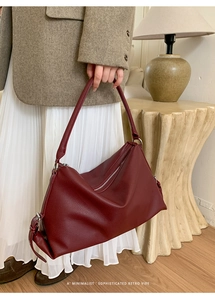 Deep burgundy leather tote bag with pebble texture held by model in retro style