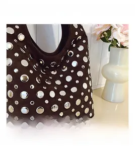 Close-up of brown suede tote bag with decorative silver metal studs and chic rivet details