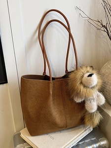 Brown suede tote bag with woven texture, shoulder straps and cute lion plush charm