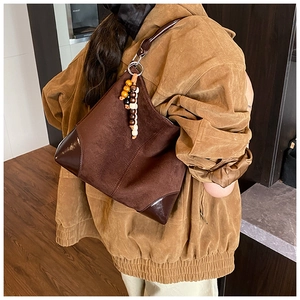 Detail of dark brown faux suede tote bag with leather corners and wooden beaded pendant