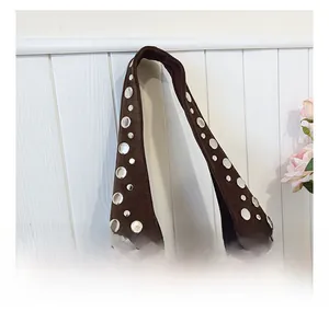 Detail of silver rivets and eyelets on brown suede hobo bag with retro punk style