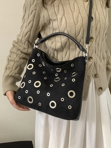 Chic black suede bucket bag with silver metal grommets for crossbody or shoulder wear