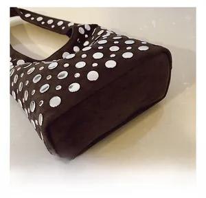 Detailed macro view of silver studs on brown suede leather bucket bag surface