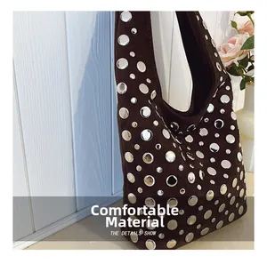 Detail showing high-quality dark brown suede texture and silver metal rivets on the handbag