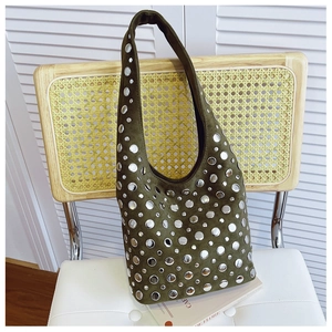 Close-up of olive green suede hobo bag with silver metallic studs hanging on a chair