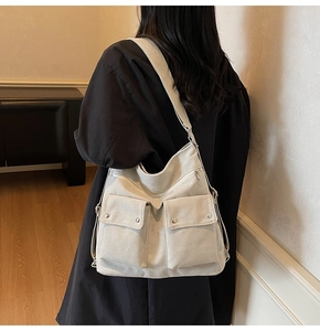 Detail of off-white canvas crossbody bag with multi-pockets worn by a model