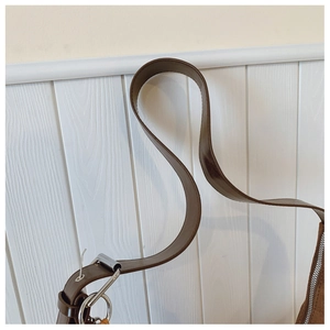 Close-up of brown suede bag strap featuring silver metal buckle and precision stitching