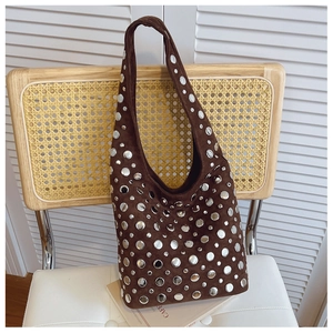 Close-up of brown suede hobo bag featuring decorative silver rivets on a vintage chair