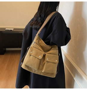 Detail of tan canvas tote bag with dual front flap pockets and adjustable wide shoulder strap
