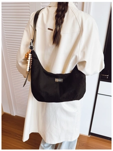 Detail of black suede hobo bag with silver logo tag and decorative wooden beads