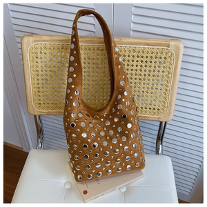 Detailed close-up of silver studs on brown suede leather shoulder bag in retro punk style