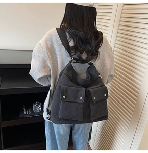 Close-up of black canvas backpack showing dual front pockets with silver snap buttons
