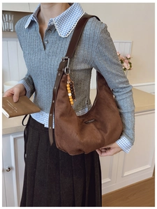 Detail of dark brown faux suede crescent bag with wooden bead charm and adjustable strap