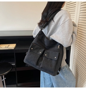 Close-up of black canvas tote bag featuring dual front pockets and adjustable wide strap
