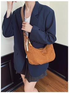 Detail of vintage brown suede crescent bag featuring wooden bead charm and leather strap