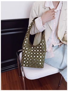 Detail of army green suede hobo bag with punk silver studs worn by a model in a studio