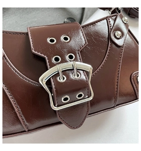 Macro detail of dark brown glossy saddle bag featuring silver metal buckle and rivets
