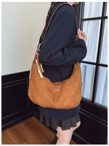 Close-up of brown suede shoulder bag with beaded fringe and fashion leather patch