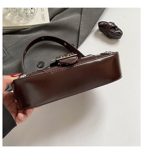 Detailed side view of dark brown saddle bag with silver buckles and adjustable strap