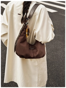 Detail view of large dark brown suede hobo bag with wide leather strap and wooden beads decoration