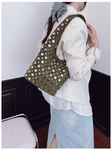 Detail of dark green suede hobo bag with silver rivets worn by a model on shoulder