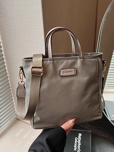 Brown nylon tote bag with wide shoulder strap and CLEAR K logo in a minimalist scene