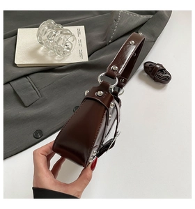 Detail view of brown leather saddle bag with silver studs and adjustable shoulder strap