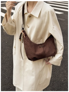 Detail of vintage brown suede crescent bag with bead charms on a fashion trench coat