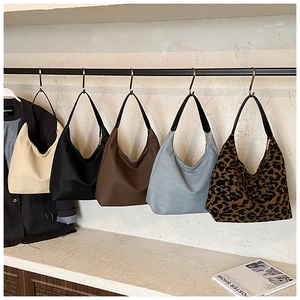 Hobo shoulder bags shown in ivory, black, brown, blue, and leopard print on a metal rack