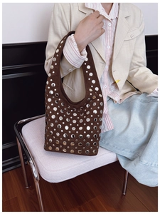 Detail of dark brown suede hobo bag with vintage silver rivets on a model
