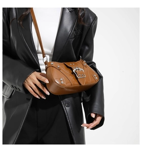Brown retro saddle bag detail with silver metal studs and large buckle on shoulder strap