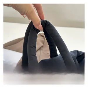 Detail showing the thick padded handle of a black nylon tote bag for comfortable grip