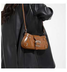 Detail of a brown retro saddle bag with silver studs and a metallic buckle on a leather jacket