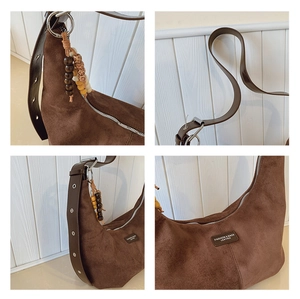 Close-up of brown suede hobo bag detailing wooden beads, leather strap, and zipper