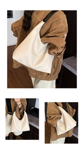Detail of a large cream hobo bag with black wide straps and textured soft fabric