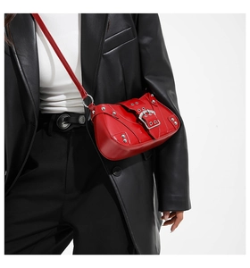 Detail of red leather crossbody bag with silver punk studs and metal buckle closure