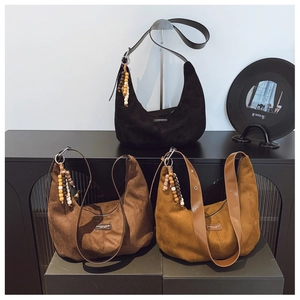 Close-up of suede tote bags in black, dark brown, and caramel with wooden bead charms