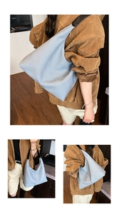 Close-up of light blue canvas tote bag with wide black shoulder strap and large capacity