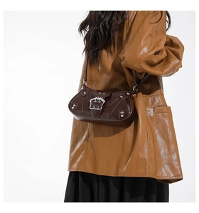 Detail of dark brown vintage saddle bag with silver metal buckle and rivet accents