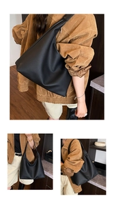 Detail of minimalist black leather tote bag showing wide shoulder strap and soft structure