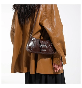 Detail of dark brown leather saddle bag with silver rivets and buckle on a model
