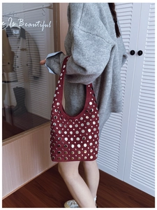 Detail of burgundy suede underarm bucket bag with silver metal studs in punk style