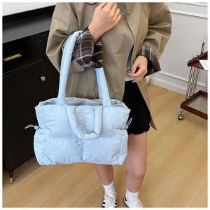 Detailed view of light blue quilted nylon tote bag with drawstring side and padded texture