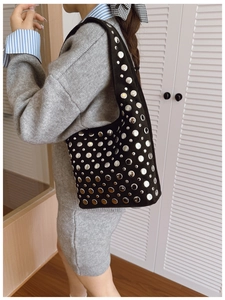 Side view of punk style black suede shoulder bag with silver studs on a female model