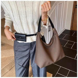 Detail einer dunkelbraunen Hobo-Tasche kombiniert mit einer schwarzen Gürteltasche